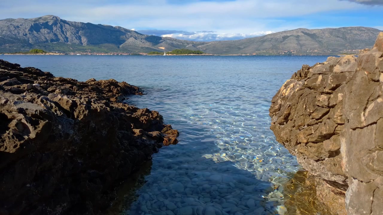 Acqua calma e limpida e piccola insenatura su spiaggia rocciosa, paesaggio marino e montano, Europa meridionale