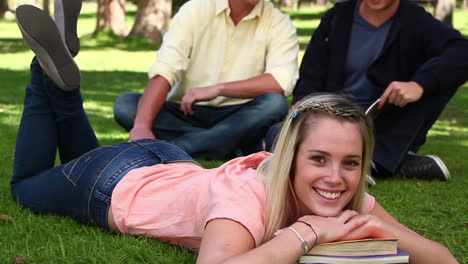 Woman-lying-on-books-with-her-legs-raised-before-opening-her-eyes-and-smiling