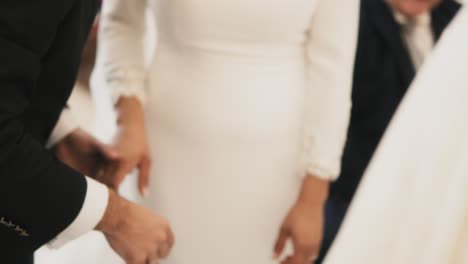 Bride-and-groom-holding-hands-at-the-wedding-ceremony,-unrecognisable-people