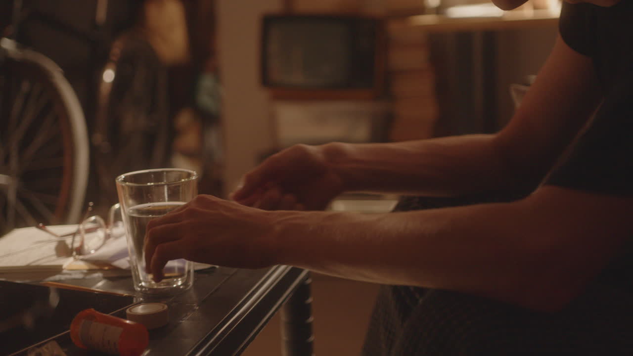 joven que toma pastillas antidepresivas y agua potable en casa