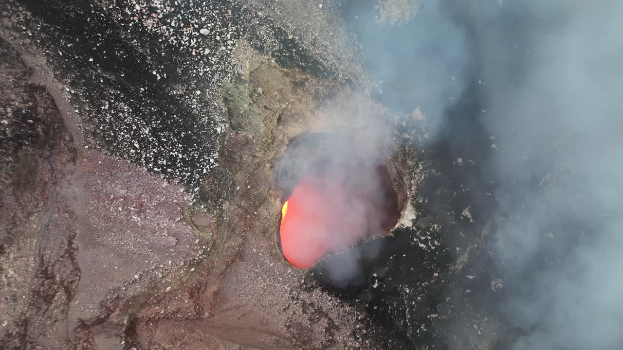 toma aérea sobre un cráter lleno de lava roja y vapor de volcán en erupción en centroamérica