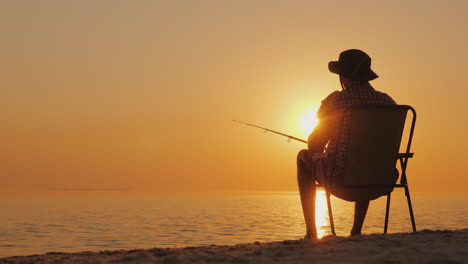 a young man is sitting on the seashore fishing relaxing in the open air 4k video