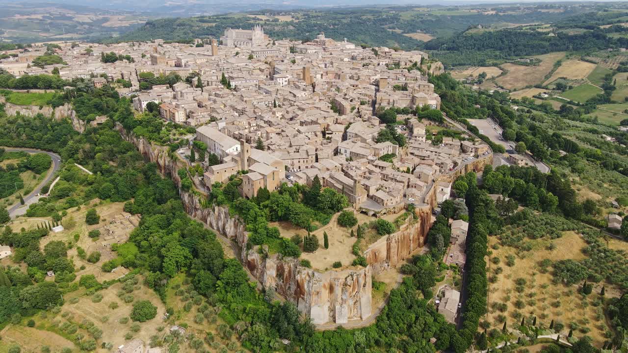 Drone backs away, ancient Italian town perched on cliffs, uncovering full layout