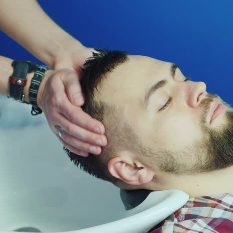 man getting hair washed and rinsed in barbershop
