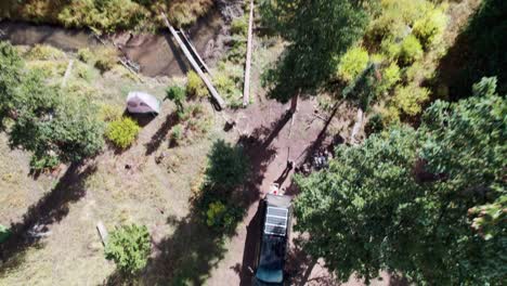 Aerial-ascent-revealing-a-campsite-where-a-truck-with-a-camper-shell-with-solar-panels-is-at-the-base-of-a-burned-mountain