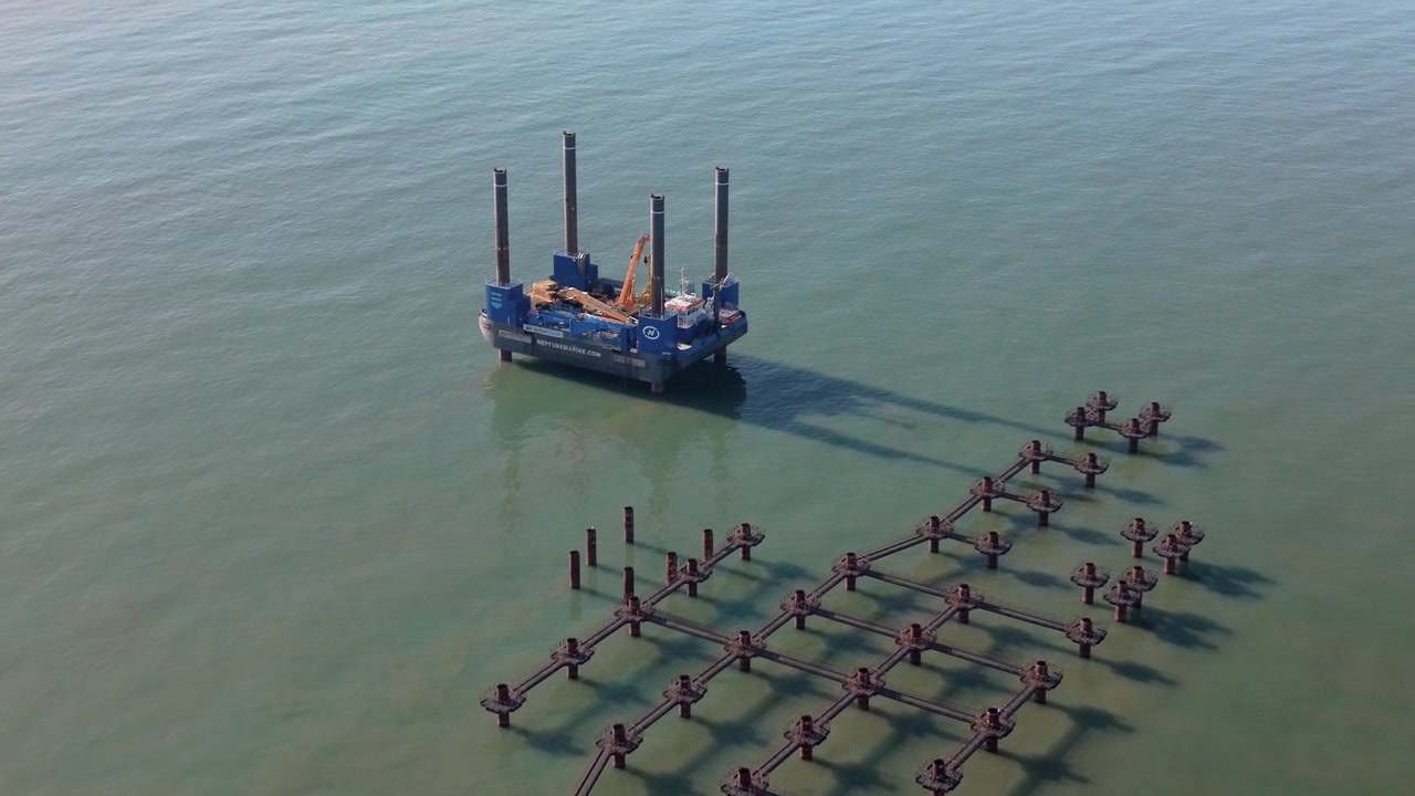 Vista aérea de una barcaza autoelevable y una plataforma de construcción marina en aguas costeras tranquilas