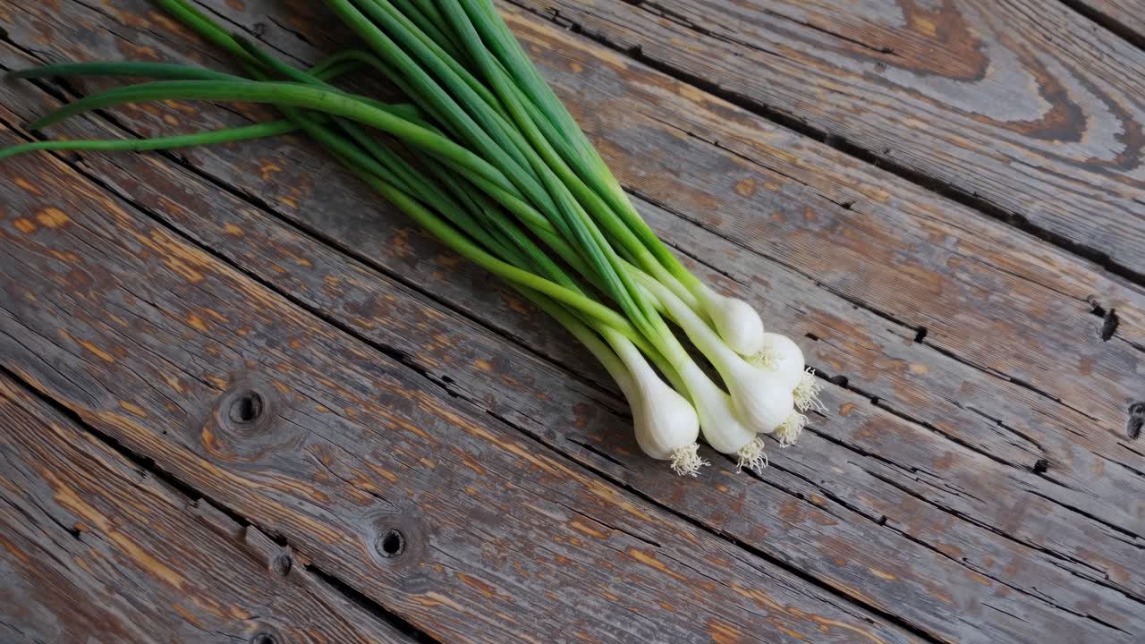 Top-down video shot of fresh green onions on rustic wooden planks, highlighting natural textures