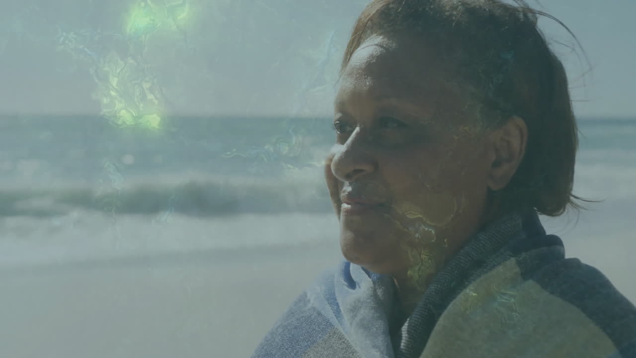 senior woman standing on beach, with floating health chart and heart icon showing wellness data