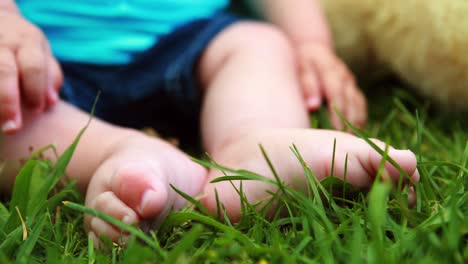 cute baby boy sitting on the grass with teddy bear