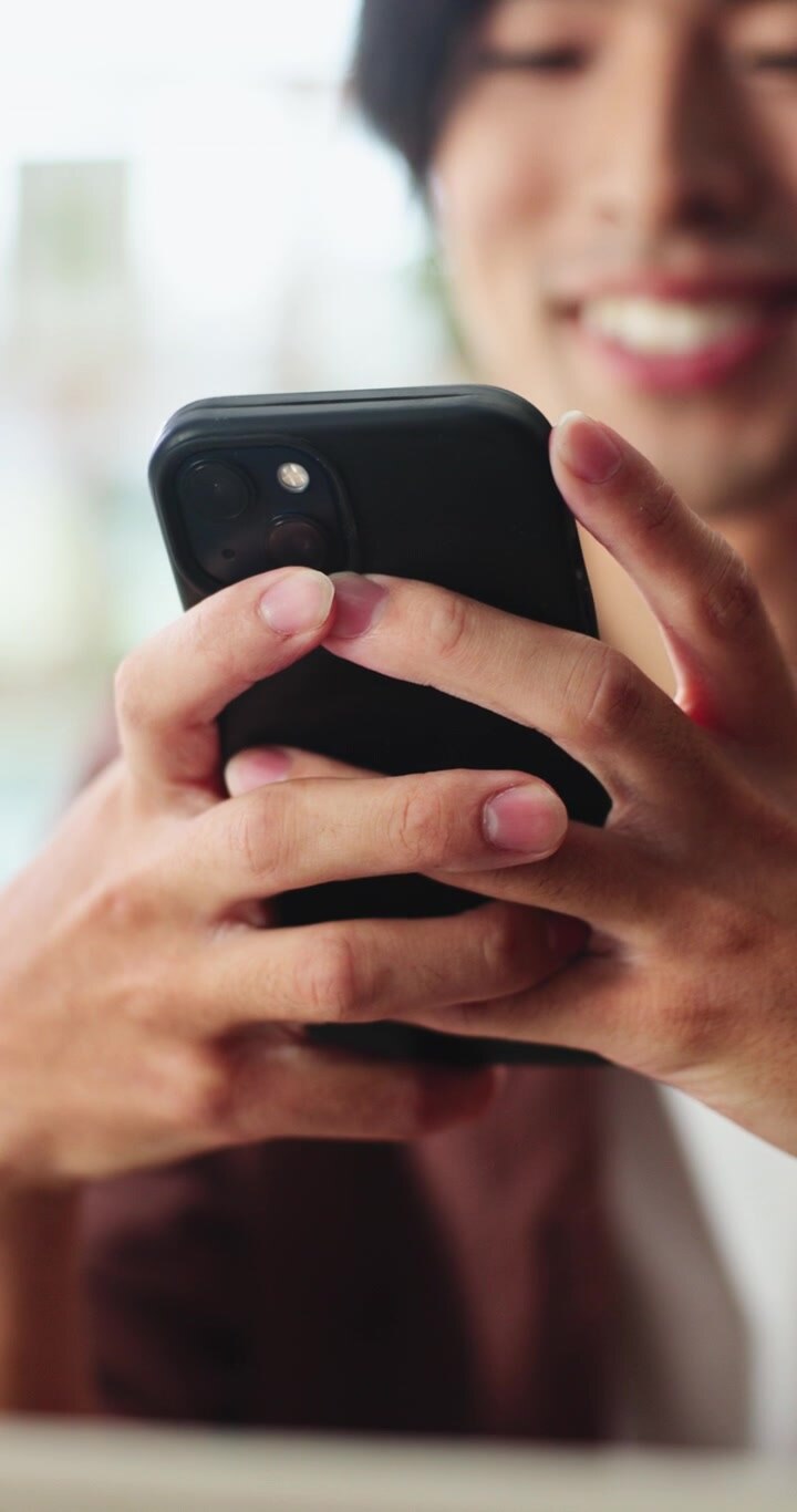 Giovane uomo sorridente che usa lo smartphone