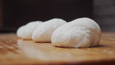 Close-up-on-the-pizza-dough-parts-layout-on-wooden-table