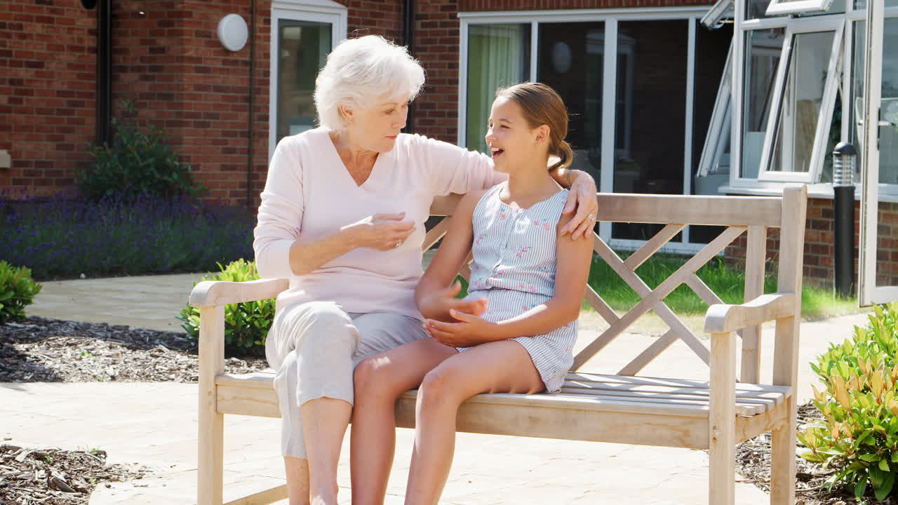 손녀 가 노인 집 을 방문 하는 동안 할머니 와 함께 벤치 에 앉아 있다