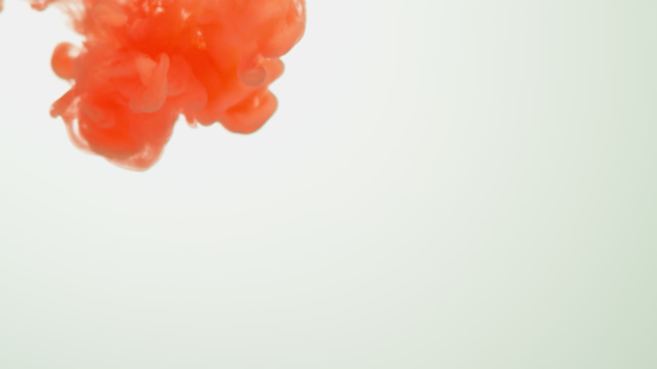 оранжевая краска или краситель, сброшенные в воду на белом фоне для создания вихревого цветного дымового фона 3