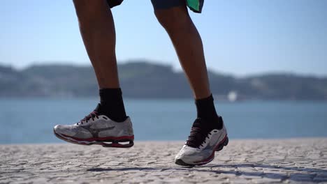 cropped shot of athletic man jogging at riverside