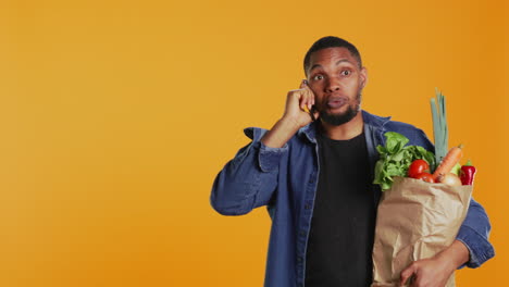 hombre afroamericano en compras de comestibles charlando por teléfono