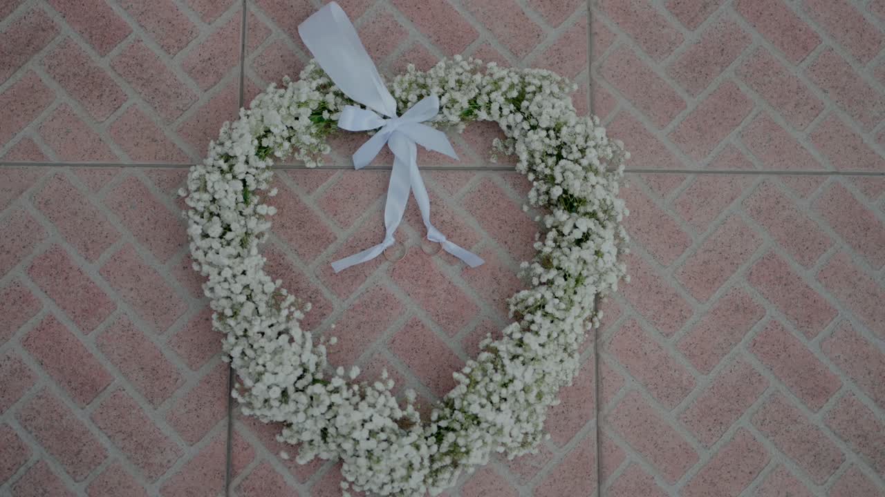 corona floral en forma de corazón con cinta blanca en la superficie de azulejos