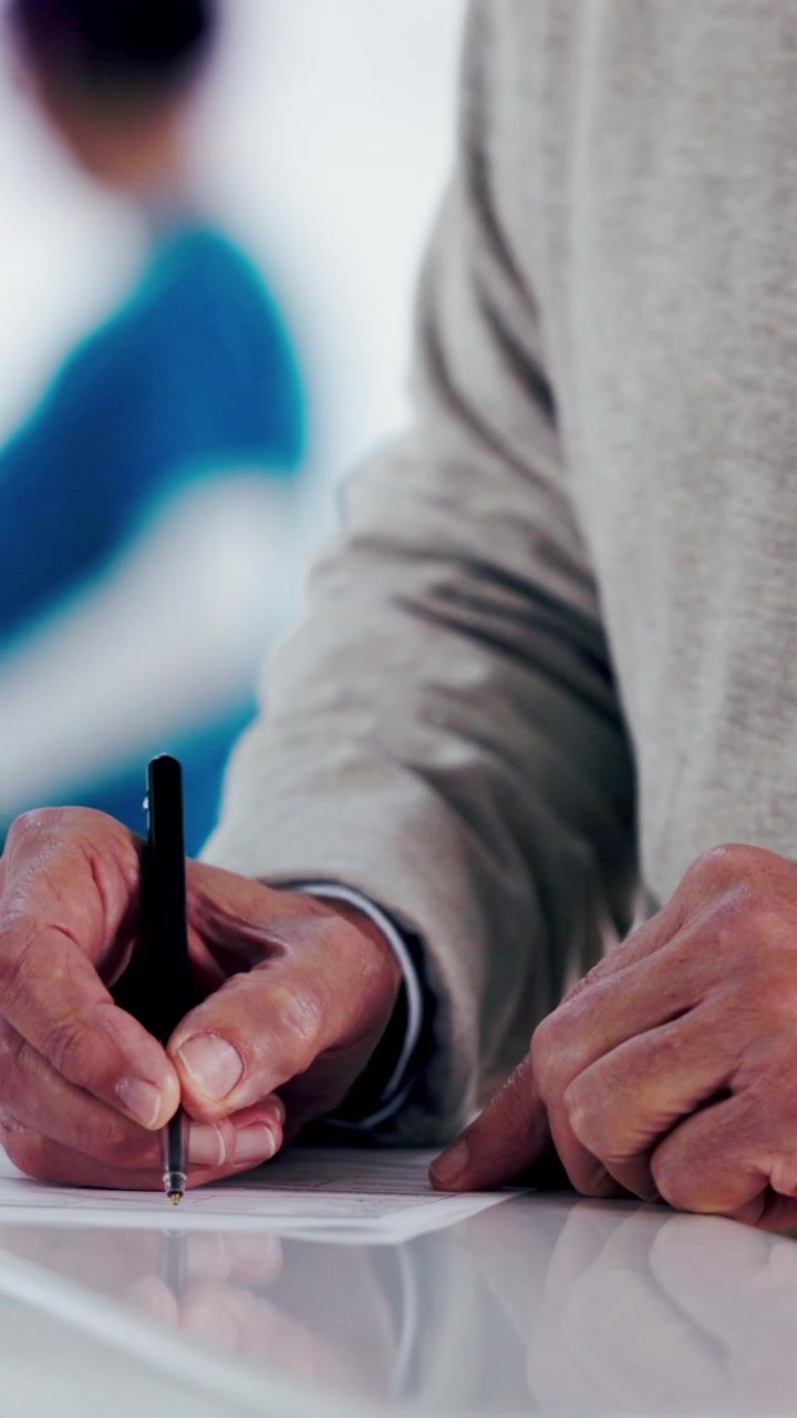 Close-up of Person Writing on Paper Document at Desk