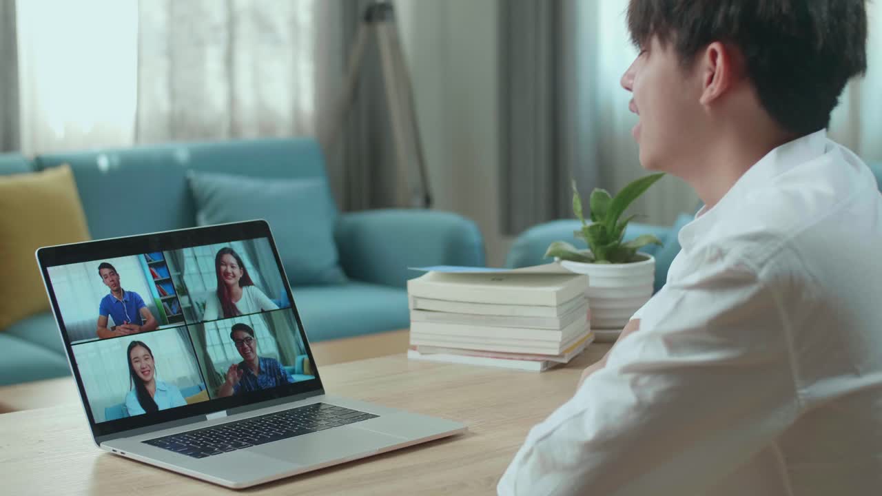 アジア人男性の学生が自宅で友達とビデオコールをしている