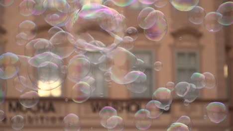 Close-up-of-colorful-soap-bubbles-flying-from-tri-string-against-house-facade-in-slow-motion