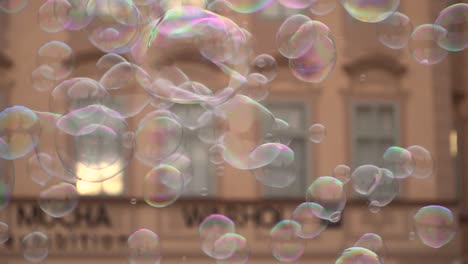 close up of colorful soap bubbles flying from tri-string against house facade in slow motion