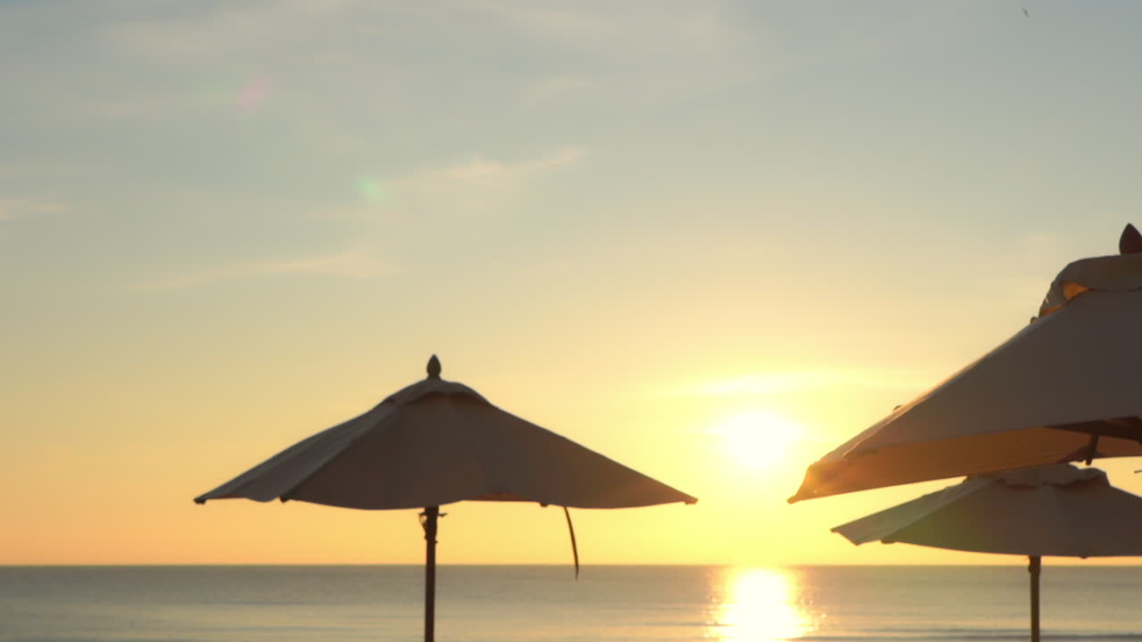 Pan across the tops of open shade umbrellas at sunset
