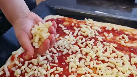 Un-Niño-Untando-El-Queso-Sobre-La-Masa-De-Pizza