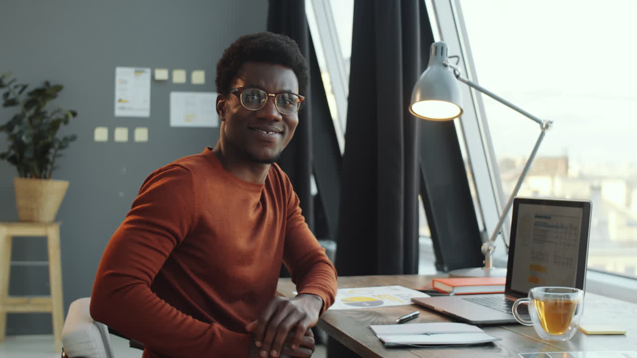 Uomo d'affari afroamericano sorridente in posa in ufficio