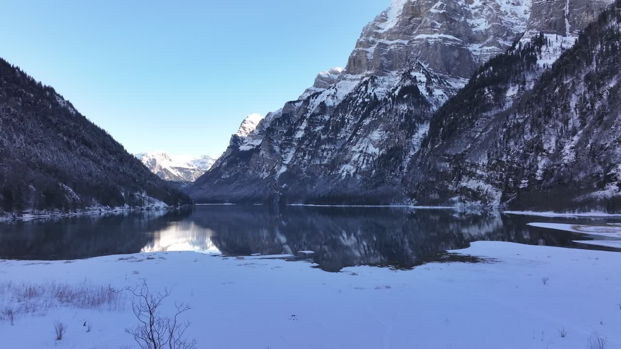 Aerial winter view of Lake Klöntalersee entirely covered in snow.