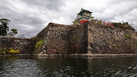 main building of osaka castle with green trees around castle in autumn, osaka