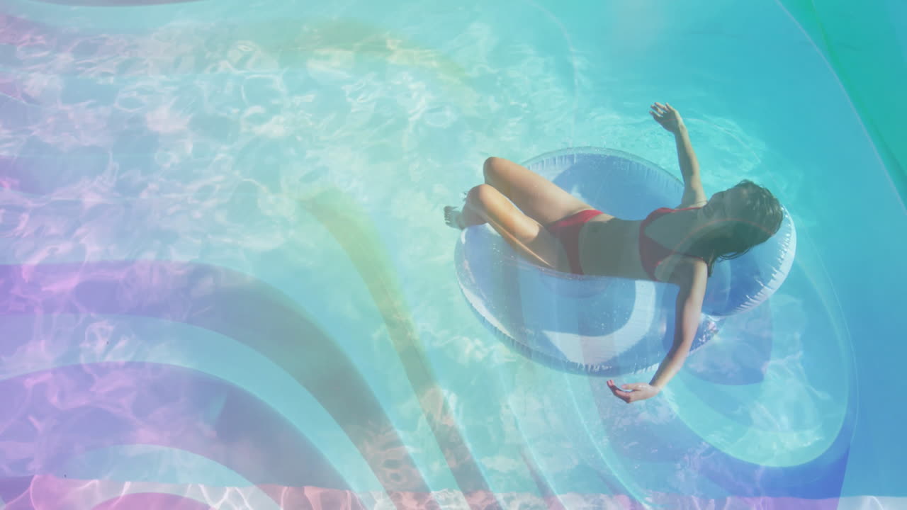 woman in red bikini reclining on pool tube in turquoise water, showcasing lens flares for marketing