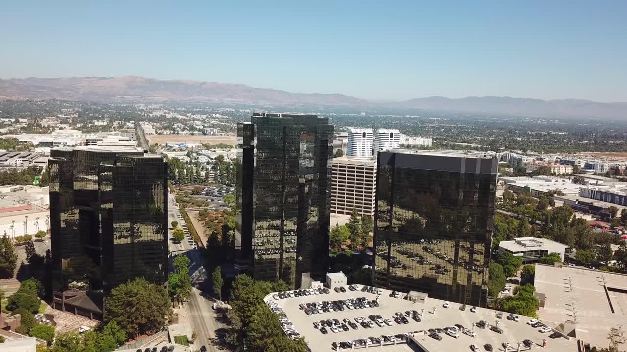 Aerial approaching shot of mirrored AIG Capital Service buildings during sunny day in autumn. Los Angeles City Suburb and mountains in background. Wide shot.