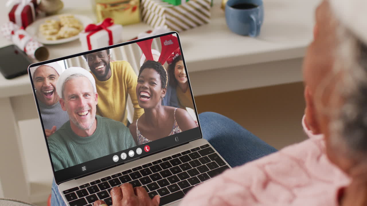 una mujer afroamericana mayor tiene una videoconferencia de navidad con personas diversas.