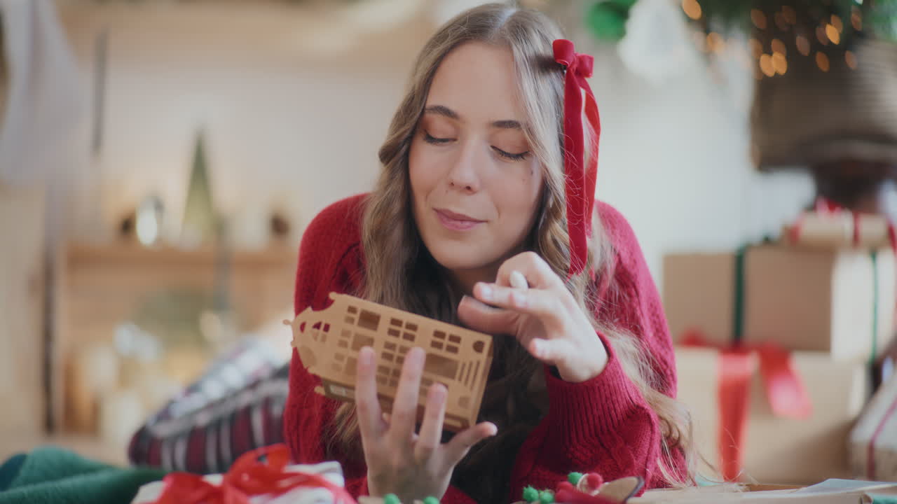 mujer coloreando un ornamento de casa de cartón mientras yacía en el suelo durante la navidad