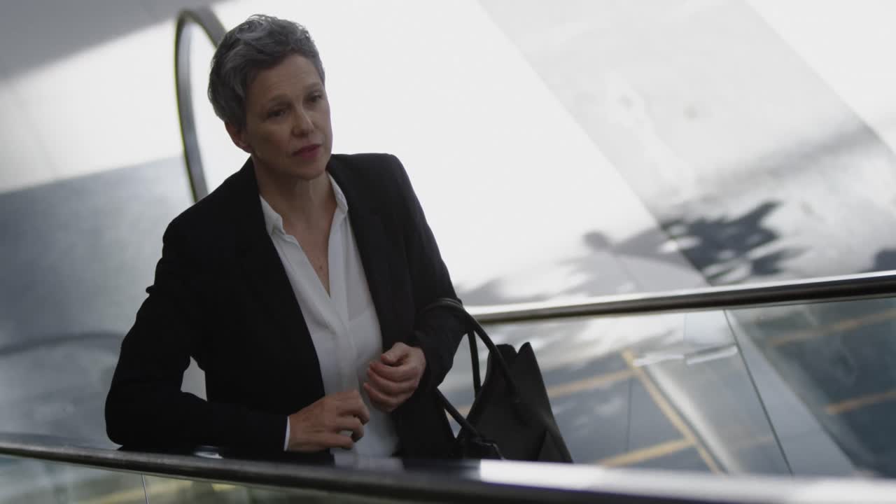 mujer de negocios usando escaleras mecánicas en una oficina moderna 4k