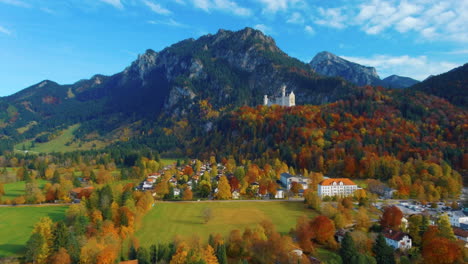 relaxing view of drone gliding up towards castle on hill over scenic autumn field in the afternoon near the neuschwanstein castle in germany, europe, wide view