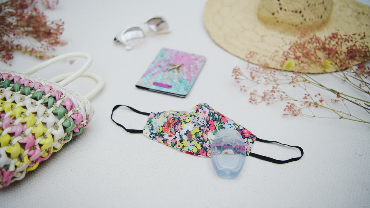 Floral face mask, travel flat lay concept, organized items for a hipster girl spread out on white table, coronavirus era
