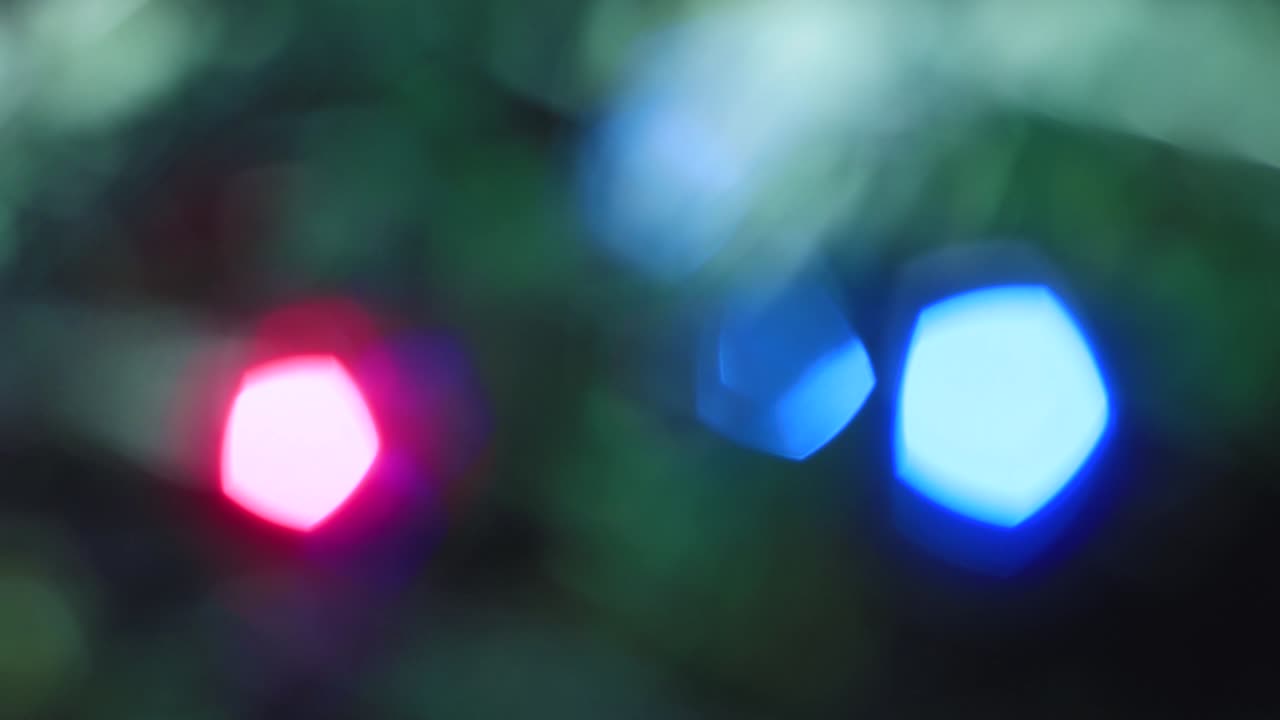 las luces multicolores de navidad parpadean lentamente fuera de foco.