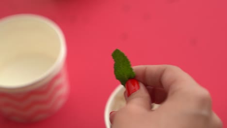 primer plano de sacar una hoja de menta del vapor para usarla como guarnición en el postre