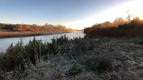 slow zoom and pan over a misty manawatu river bathed in the suns early morning golden glow