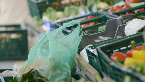 close-up view of green plastic bags at a market with various vegetables