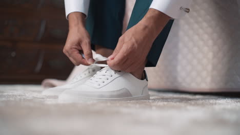 person tying laces on white sneakers