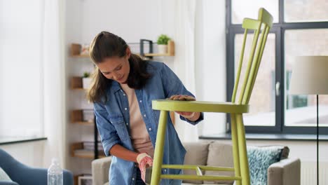 furniture-renovation,-diy-and-home-improvement-concept--happy-smiling-mother-and-daughter-sanding-old-round-wooden-chair-with-sponge-at-home