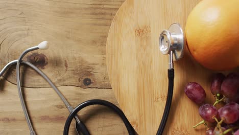 Video-of-close-up-of-stethoscope-with-fruit-on-wooden-table