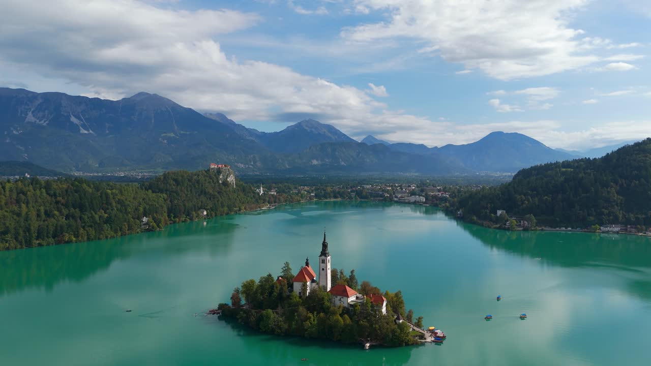 Aerial: view of lake Bled Island with Bled castle in the distance during the day in Bled, Slovenia, dolly out drone shot