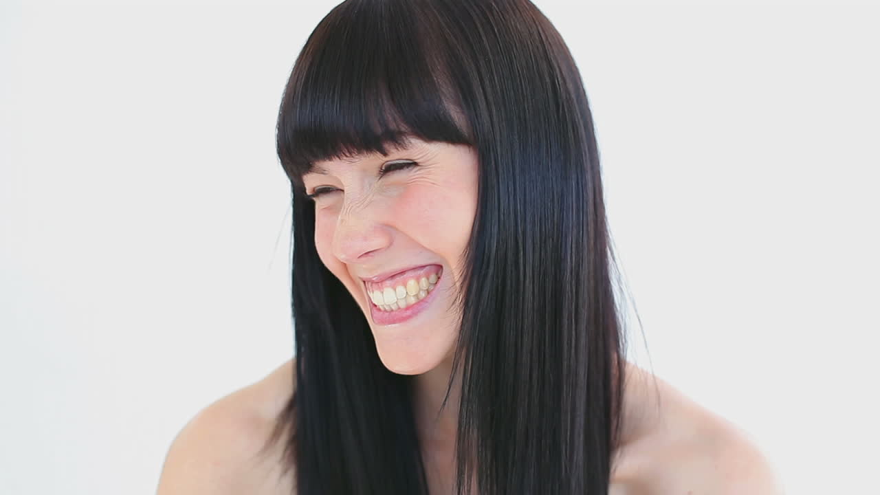 Happy woman combing her hair while laughing