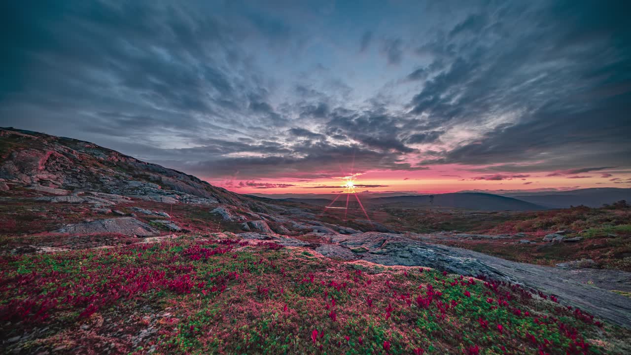 The red setting sun moves slowly on the horizon and above the autumn tundra, lighting the clouds with a reddish glow