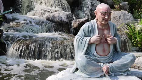 statue of a monk meditating by a waterfall