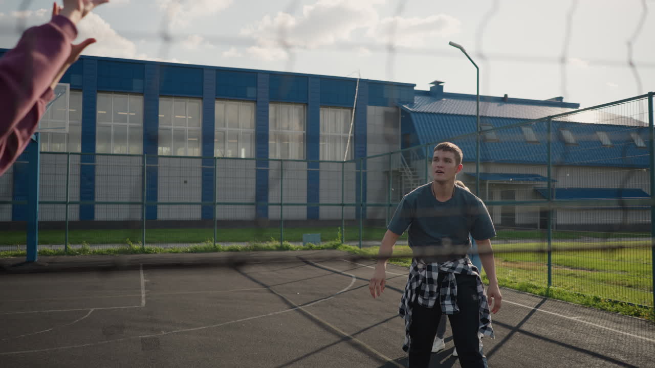 배구 선수는 훈련 세션에서 여자에게 공을 제공, 누가 그것을 다시 slams, 그는 slam을 위해 뛰어, 야외 코트에서 배경에 다른 플레이어의 흐릿한 시야