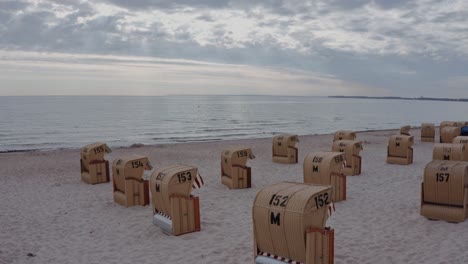 Abendliche-Meereslandschaft,-Die-Gelassenheit-Und-Stille-Mit-Ausgebreiteten-Strandkörben-An-Einem-Einsamen-Strand-Unter-Bewölktem-Himmel-Inspiriert