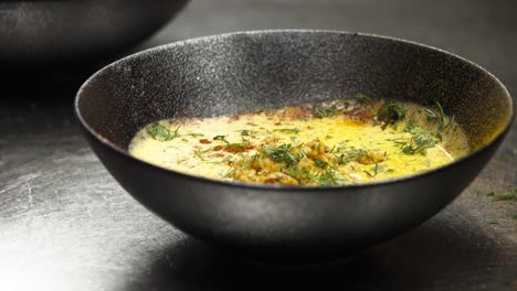 chef garnishing soup with herbs in kitchen, close-up